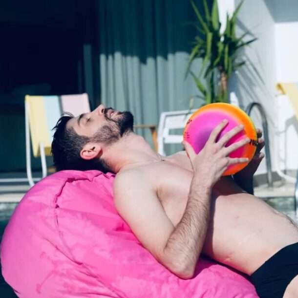 Scape Hotel - boy paying on a fluffy chair by the pool holding a ball