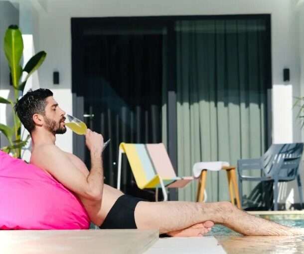 Scape Hotel - boy sitting on a beany having a cocktail by the pool